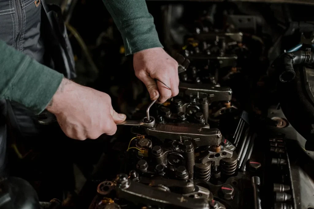 Mobile RV repair technician fixing a water pump under an RV at a campsite, surrounded by tools and equipment